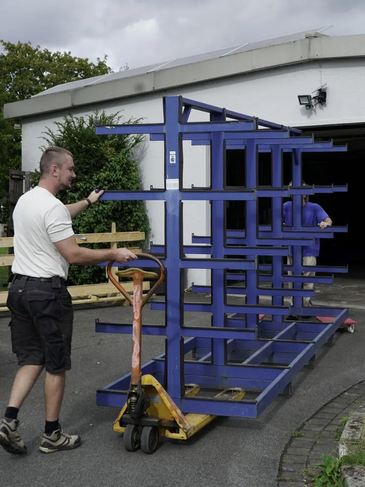 Buildora-Team beim Transport eines Regals vor der Halle