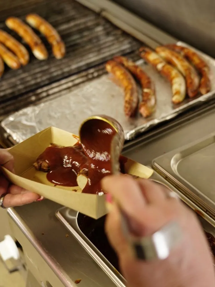 Currysauce wird bei CurryCo über die Wurst gegeben